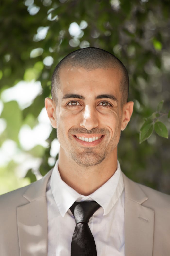Services Portrait of a smiling business professional outdoors with greenery background.