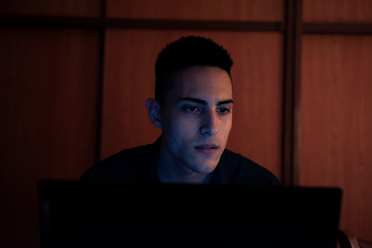 Services Young man working on a laptop indoors at night in Buenos Aires, capturing focus and concentration.